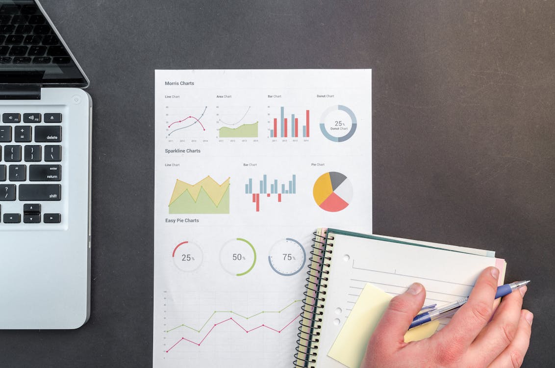 Free Overhead view of a business desk with charts and a laptop, ideal for data analysis concepts. Stock Photo